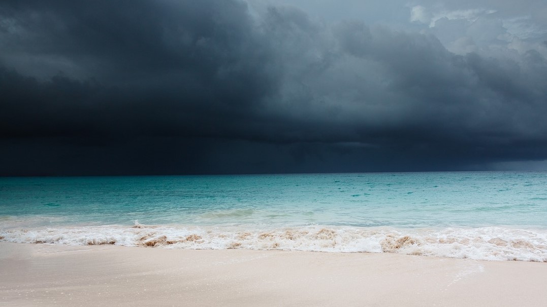 Photo of a beach with a storm brewing over the sea. 