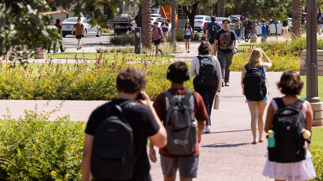 ASU students walking on a path on campus with foliage lining the path. 
