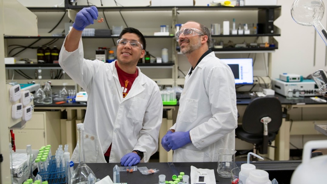 Sergi Garcia-Segura (right), an assistant professor of civil, environmental and sustainable engineering in the School of Sustainable Engineering and the Built Environment, part of the Ira A. Fulton Schools of Engineering, and a student research assistant (both wearing protective lab coats, safety glasses and gloves) examine equipment in Garcia-Segura’s laboratory on ASU's Tempe campus. 