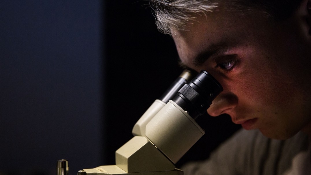 Image of a man peering into a microscope 