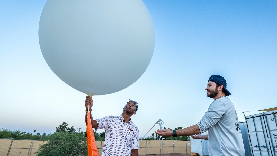 ASU Foundation Professor Vernon Morris holds a 4-foot, helium-filled latex meteorological balloon as field engineer Mark Manriquez assists. 