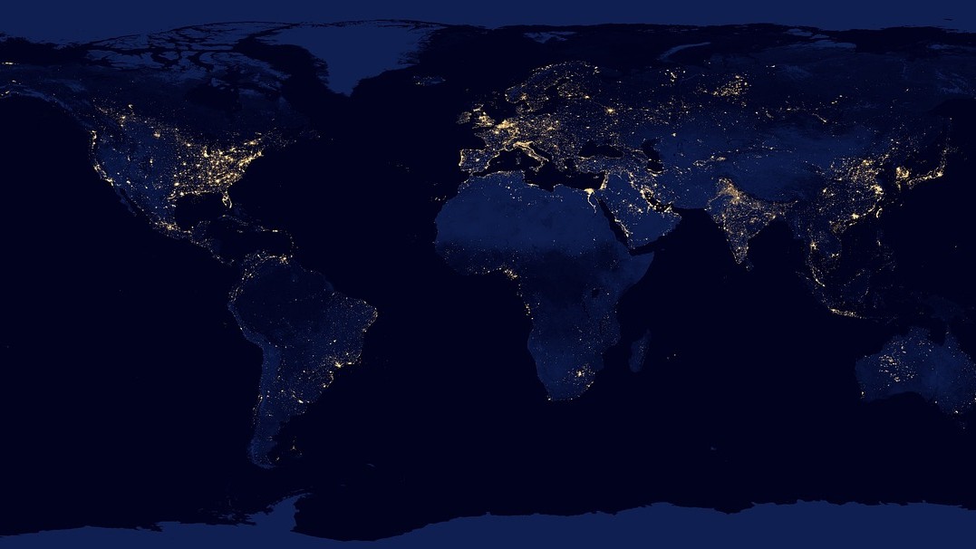 Image of the Earth taken at night with clusters of light visible on continents 