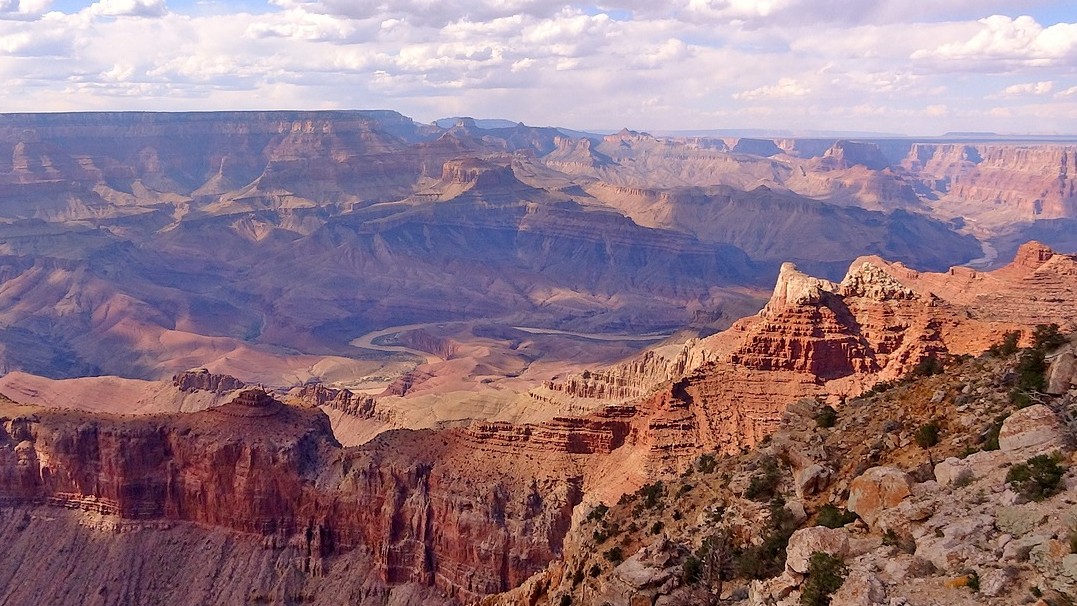 Image of the Grand Canyon with clouds in the distant sky and the rim of the canyon in the distance. 