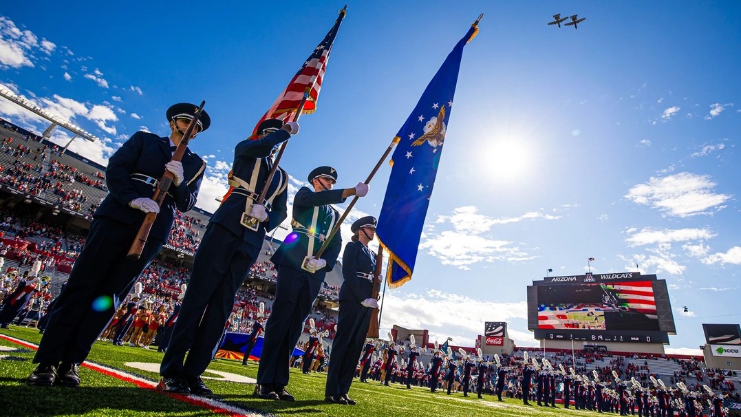 University of Arizona Air Force ROTC cadets in full uniforms and carrying flags perform their color guard duties before a University of Arizona football game. 