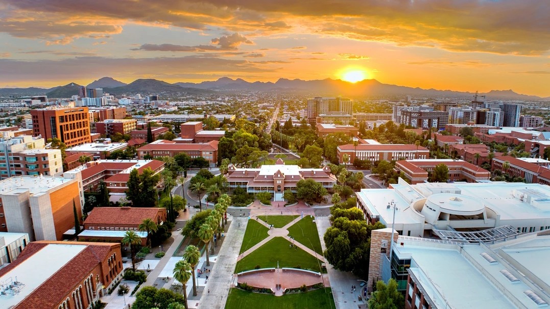 View of the U of A campus with the sun setting in the background and clouds in the sky 