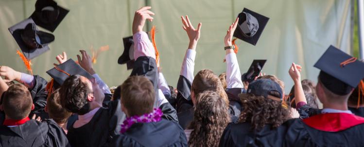 Photo of graduates throwing their caps in the air. 