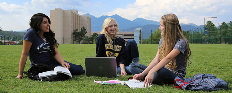 Three NAU students siting on grass studying