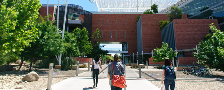 Photo of three students walking toward a building on the University of Arizona campus