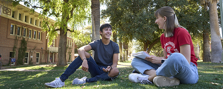 Photo of two students on campus relaxing outside 