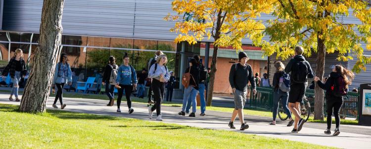 photo of students walking on campus with colorful trees in the distance. 