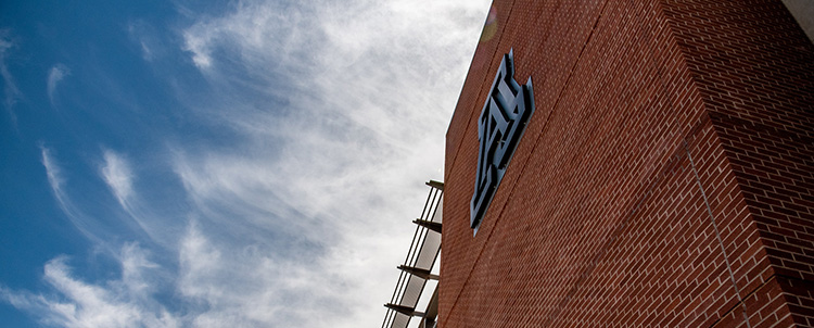 Image of the A on a University of Arizona building with clouds in the sky visible 